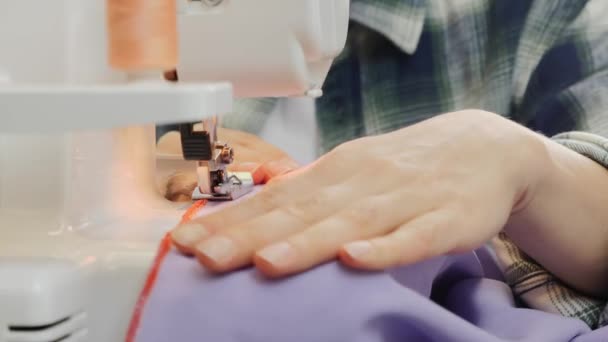 Згорніть пальці жінки, які шиють на швейних машинах. Деталі швейних машин. Жінка перекриває тканину. Магазин на швейній тканині. Створення і пошиття одягу. — стокове відео