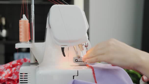 Woman sewing dress on sewing machine. Close up of female hands sew on overlock. Workshop in sewing fabric. Creation and tailoring clothes — Stock Video