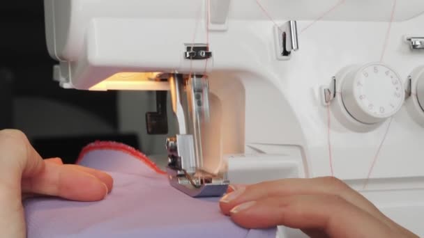 Overlock 'u dikerken ellerinizi kapatın. Profesyonel terzi çalışıyor ve elbise yapıyor. Yaratılış ve terzilik kıyafetleri. Kumaş dikme atölyesi — Stok video