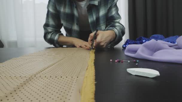 Mujer cortando tela con tijeras en el estudio del sastre, rebanada de jabón, alfileres de seguridad acostados en la mesa. El primer plano de las tijeras corta la tela. Creación y confección de ropa. Concepto de moda — Vídeos de Stock