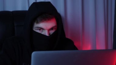 Ekrana bakan ve bilgisayardaki şifreyi kıran profesyonel bir hacker. Dizüstü bilgisayar ekranına ve kodlama senaryolarına bakan erkek yüzünü kapat. Bilgisayarda insan programlama. Çevrimiçi güvenlik koruması