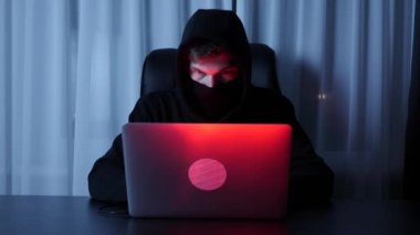 Bilgisayar ekranına bakan hacker suratı. Siyah maskeli bir erkek, şifre kırıcı ve çevrimiçi sosyal güvenlik koruması. Dizüstü bilgisayardaki hacker programlama senaryoları. Güvenlik ve viral konsept