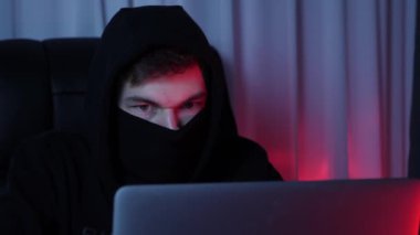 Ekrana bakan ve bilgisayardaki şifreyi kıran profesyonel bir hacker. Dizüstü bilgisayar ekranına ve kodlama senaryolarına bakan erkek yüzünü kapat. Bilgisayarda insan programlama. Güvenlik kavramı. Yavaş çekim
