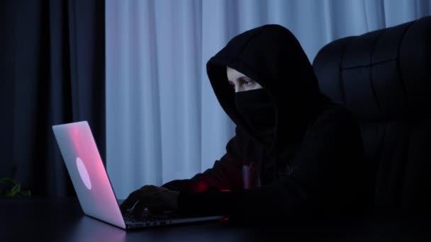 Hacker quebrando proteção de segurança on-line no computador. Feminino em máscara preta e codificação com capuz e programação na tela do laptop. Hacker digitando no teclado. Online, vírus, conceito de desenvolvimento web — Vídeo de Stock