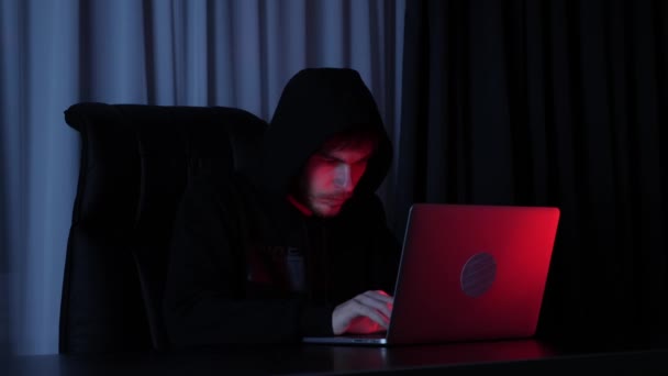 Professionele informatietechnicus typt op laptop. Mannelijke hacker in zwarte hoodie codering op het scherm en het breken van wachtwoord. De man streelt sleutels op de computer. Begrip veiligheidsbescherming. Langzame beweging — Stockvideo