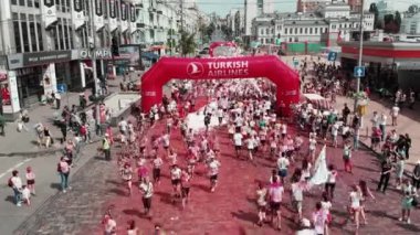 Kyiv/Ukraine - June 2, 2019 - People smeared colorful fluorescent holi paints running at Color Run Kyiv festival. Drone flying around arch 