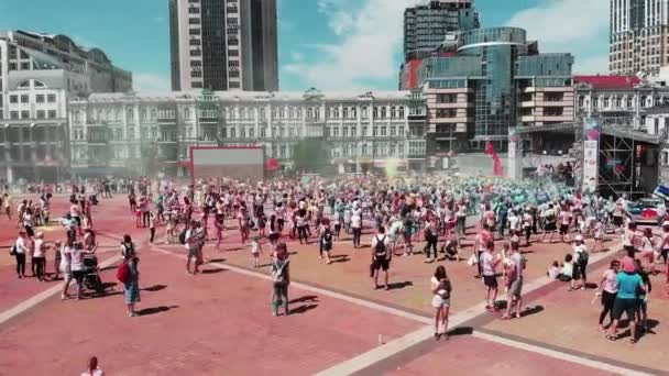 Kiev / Ucrânia - 2 de junho de 2019 - Fêmeas e machos manchados em tintas holi coloridas dançando perto do palco no festival Color Run Kyiv. Feliz sorrindo as pessoas na corrida corrida, visão aérea drone . — Vídeo de Stock