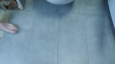 Çıplak ayaklı bir adam banyodaki beyaz tuvalete oturur. Tuvalette oturan kot pantolonlu erkeklerin ayaklarını kapat.