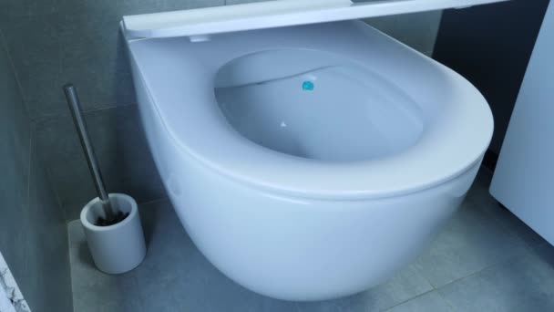 변기 뚜껑이 닫히는 것을 가까이 서 보라. 화장실에 있는 하얀 변기를 가까이 서 볼 수있다. 벽 과 바닥에 흰 변기와 회색 타일 이 있는 화장실의 일부 — 비디오