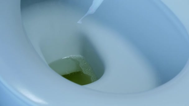 Male hand flushes urine in white toilet bowl, close up. Side view of white toilet in bathroom with grey tiles. Water flushing down into the toilet bowl in bathroom. Water flushed in toilet — Stock Video