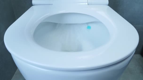 Toilet putih, tampilan depan. Tutup pandangan air yang mengalir ke dalam mangkuk toilet di kamar mandi dengan ubin abu-abu di dinding dan lantai. Air memerah dalam mangkuk toilet — Stok Video