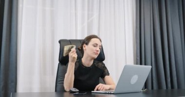 Başarılı zengin iş kadını bir tomar banknotla oturuyor. Genç bayan patronun elinde dolar banknotları var. Başarı iş konsepti