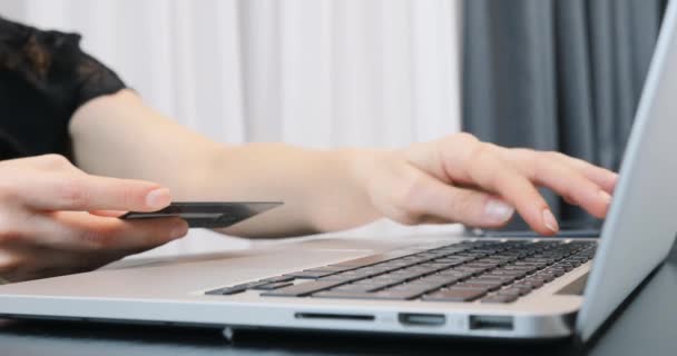 女性の手はノートパソコンに銀行カード番号を入力します。女性はオンラインショッピングにお金を払う。資金決済の概念 — ストック動画
