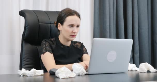 Beteg nő, aki laptopon dolgozik az irodában, koszos szalvétákkal körülvéve. Nő folyós orral gépel a billentyűzeten. Irodapult laptoppal és piszkos szalvétával — Stock videók