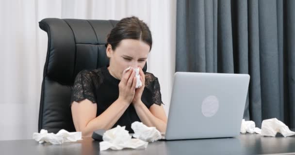 办公室里流鼻涕的女人女人坐在写字台前擦鼻涕.有流鼻涕的女商人在办公室工作。手持纸巾的生病妇女在笔记本电脑上工作 — 图库视频影像
