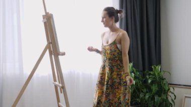 Güzel kadın ressam, tuvale ince bir fırça kullanarak resim yapıyor. Sanat atölyesinde tuval. Soyut resim üzerinde çalışan bir kadın. Tuvale resim çizen kız. Sanat akademisi veya çizim okulu