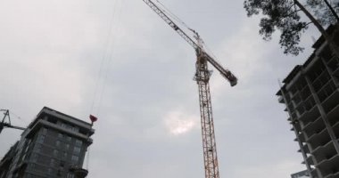 Yüksek vinç inşaat alanında çalışıyor. Binaları inşa edin. Vinçli gökdelenin inşaat süreci. Yüksek binalar yapım aşamasında.