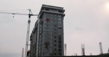 İnşaat alanında çalışan işçiler. İnşaatçılar bir ev inşa ederler. Yüksek vinçli inşaat alanı