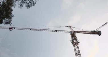 Yüksek vinç şantiyede çalışıyor. Gri gökyüzüne ve bulutlara karşı inşaat vinci. İnşaatın zamanı.