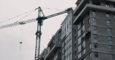 Bina yüksek vinçle yapım aşamasında. İnşaatçılar ev yapar. İnşaat alanında çalışan yüksek vinç