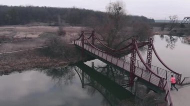 Köprüde tek başına koşan kadın, hava manzaralı. Kadın sabah River 'la parkta koşuyor. Parlak spor elbiseli bir kız nehirde köprüde koşuyor.