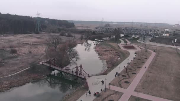 Fußgängerzone mit Menschen entlang des Flusses, Drohnenblick aus der Luft. Drohne fliegt über Fluss mit Brücke und Promenade — Stockvideo