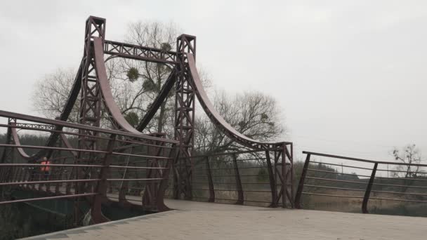 Donna e uomo finiscono l'addestramento al parco. Giovane coppia sportiva che corre attraverso il ponte nella giornata nuvolosa grigia. Atleti che fanno attività mattutina all'aperto — Video Stock