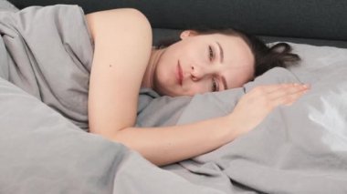 Kadın uyanıyor ve kameraya bakıyor, kapat. Güzel gözlü çekici bir kadın yatakta uzanmış kameraya bakıyor. Esmer kızın portresi yatağa uzanıyor ve kameraya bakıyor.