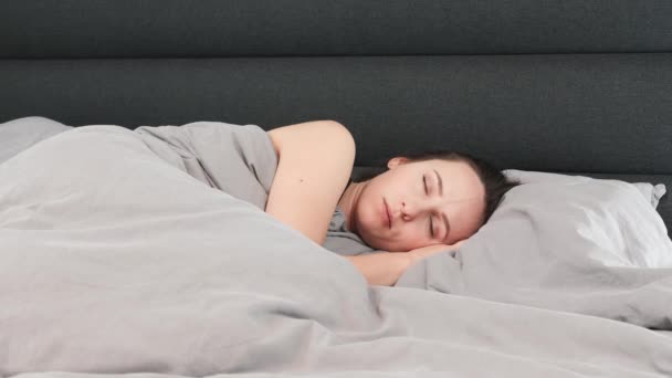 Jeune belle femme couchée sur le lit et regardant la caméra. Portrait de charmante fille brune sur le lit sourit et regarde la caméra — Video