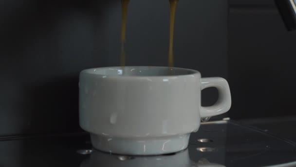 Taza blanca con café expreso lleno, vista lateral. Gotas de café se vierten en una taza pequeña — Vídeo de stock