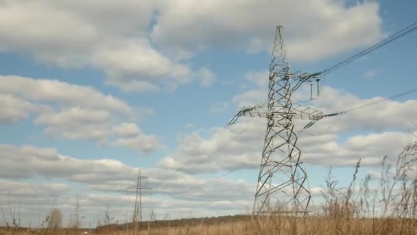 Pilão elétrico de alta tensão contra o belo céu no campo. Torres de transmissão. Pilões de electricidade. Linha de energia e fios contra o céu azul com nuvens. Concepção de eficiência energética — Vídeo de Stock