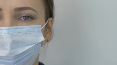 Covid-19 koronavirüsünün pandemik koruması. Koruyucu tıbbi maske takan genç bir kadının portresi. Beyaz kadın virüs enfeksiyonunu önlemek ve korumak için mavi maske takıyor.