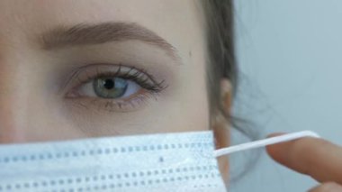 Kadın yüzüne aşırı yakın çekim virüsün önlenmesi ve korunması için koruyucu tıbbi maske takıyor. Tıbbi maskeli genç bir kadın. Salgın virüsü paniği, koronavirüs salgını tehlikesi