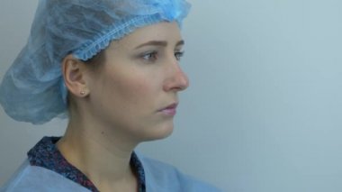 Genç bayan doktor, virüs enfeksiyonunun önlenmesi ve korunması için cerrahi müdahaleden önce tıbbi maske takıyor. Üniformalı kadın bilim adamı işe hazırlanıyor. Salgın. Coronavirus. Covid 19