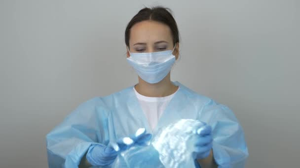 A női orvos orvosi sapkát vesz fel a műtét előtt a klinikán. Orvosi egyenruhás nő portréja, védőmaszk és gumikesztyű. Kozmetikus munka előtt — Stock videók