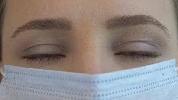 Ung kvinna ansikte bär skyddande medicinsk ansiktsmask i karantän tid för virusinfektion förebyggande och skydd. Rädsla, panik av epidemiskt virus — Stockvideo