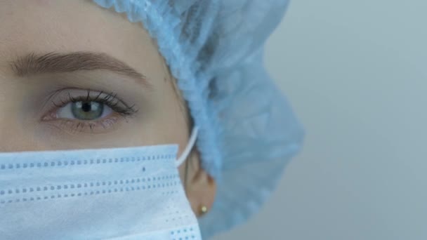 Retrato de una joven científica en gorra médica, uniforme médico y mascarilla protectora. Cara de mujer con máscara médica y gorra para la prevención y protección de infecciones por virus. Coronavirus. Covid-19 — Vídeos de Stock