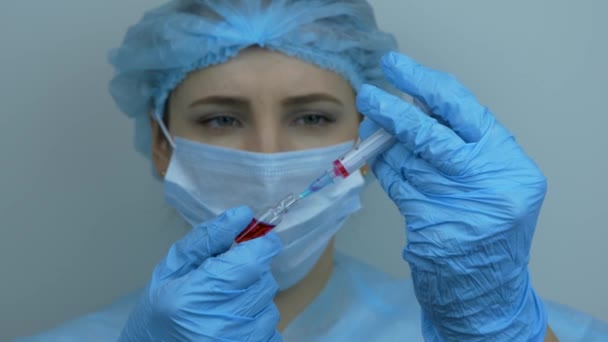 Технік ретельно готує шприц для ін'єкцій. Жінка-працівниця тримає трубку з превентивними ліками для вірусу COVID 2019-nCoV. Шприц для медсестри з наркотиками для ін'єкцій, крупним планом — стокове відео