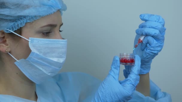 Вакцинация коронавирусом. Женщина-лаборант в защитном медицинском снаряжении держит шприц с профилактическими препаратами для инъекции вируса COVID 2019-nCoV. Врач наполняет шприц лекарствами для инъекций — стоковое видео