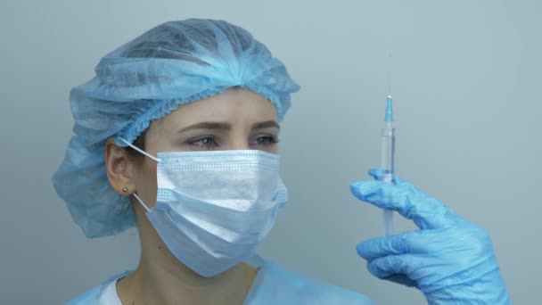 Портрет медсестры, держащей шприц с лекарствами для инъекций. Пандемия коронавируса Ковид-19. Защита от вирусов и вакцинация. Лаборант в защитном снаряжении со шприцем для инъекций — стоковое видео