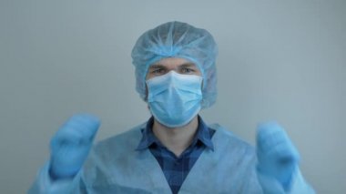 Koruyucu tıbbi teçhizatlı adam ameliyattan sonra tıbbi maskesini çıkarıyor. Virüs enfeksiyonunun önlenmesi ve korunması için mavi maske takan erkek doktor. Covid-19 'un pandemik koruması