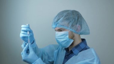 Erkek doktor enjeksiyon için şırıngayı ilaçla dolduruyor. Koruyucu ekipmanlı bilim adamı enjeksiyon için şırınga hazırlıyor. Covid 19 aşısı. Koruyucu ilaçlar. Covid-19 'un pandemik koruması