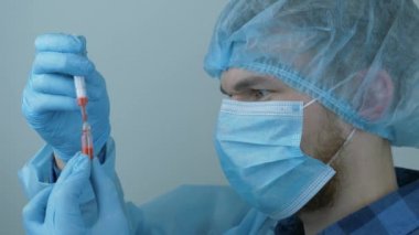 Erkek hemşirenin portresi şırıngayla enjeksiyon için ilaç taşıyor. Covid-19 koronavirüsünün pandemik koruması. Virüs koruması ve aşı. Enjeksiyon için şırınga ile koruyucu ekipmanda laboratuvar.