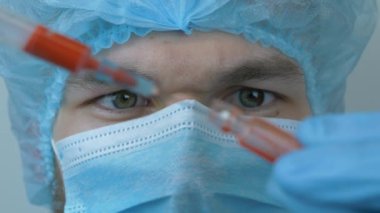 Coronavirus covid-19. Enjeksiyon için erkek doktor elinde şırınga tutuyor. Koronavirüs aşısını tedavi et. Koruyucu giysili adam test tüpünü enjeksiyon için ilaçlarla dolduruyor. Zatürree salgını