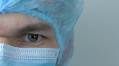 Koruyucu tıbbi maske takan genç bir erkek, yakın çekim. Covid-19 koronavirüsünün pandemik koruması. Virüs enfeksiyonu önleme ve koruma için tıbbi yüz maskesi takan adam.