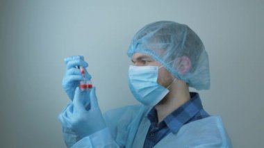Coronavirus covid-19. İğne için elinde şırınga tutan bir erkek. Koronavirüs aşısını tedavi et. Enjeksiyon için şırıngayı ilaçlarla dolduran koruyucu donanımlı bir doktor. Zatürree salgını