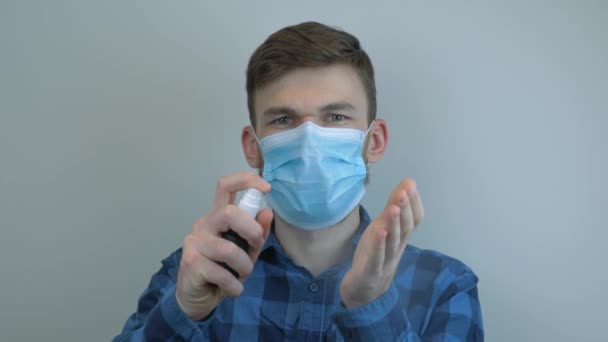 細菌やコロナウイルスから保護するために手に防腐剤を噴霧保護医療用マスクの男。男性はきれいな手のための手の消毒剤ゲルを使用しています。適切な流行の予防策。きれいな手のヒント — ストック動画