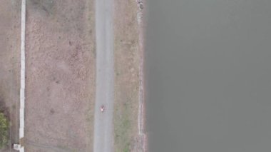 Çakıl taşı bisikleti üzerinde tek başına baraj boyunca bisiklet süren bir bisikletçi. Bisiklet sürücüsü barajla boş yolda pedal çeviriyor. Karantina sırasında tek başına bisiklete binmek. Triatlet antrenmanı ve Demir Adam yarışmasına hazırlanma