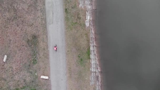 Ciclista equitação perto da barragem, drone vista superior. Mulher de bicicleta vestuário ciclismo ao ar livre em bicicleta de cascalho. Triatleta profissional pedalar duro em bicicleta de estrada no parque com lago. Conceito de desporto — Vídeo de Stock