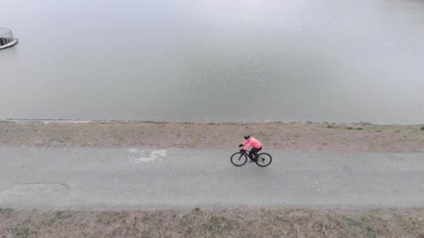 Professionell vägcyklist trampar ensam utomhus. Isolerad cykling under karantänen. Säkerhetstur på cykel. Kvinna cykling på cykel på tom väg längs dammen. Triathlete träning för mästerskap — Stockvideo